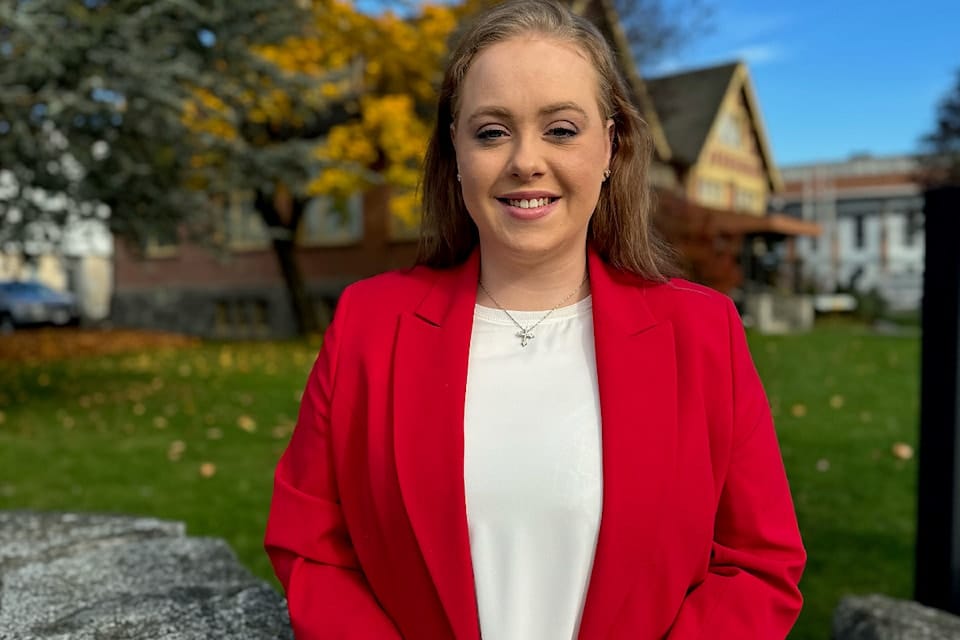 A photo of a woman, Madison Fleischer, wearing a red jacket and a cross necklace